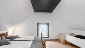 A high-ceilinged attic bedroom with a skylight, a wooden bed, a white bedside table, and a built-in bench. - Awesome home in øster assels with WiFi (Øster Assels)