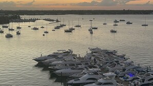 A marina with numerous boats docked, a calm water surface, and a distant city skyline at sunset. - Cozy Studio with the Best Miami Skyline Views and free parking (North Bay Village)