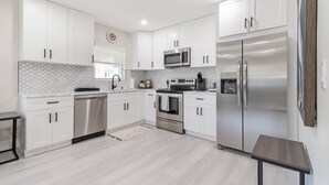 A modern kitchen with white cabinets, stainless steel appliances, a microwave, oven, and refrigerator. - TWO Casitas | Victoria Park | 30+ Night Stays Only (Fort Lauderdale)