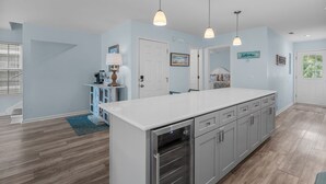 A spacious kitchen with a large island, modern pendant lights, and a view of the living area. - Island Girl-Beautiful 4BD Ocean View-Private Pool-Pet Friendly (Surfside Beach)