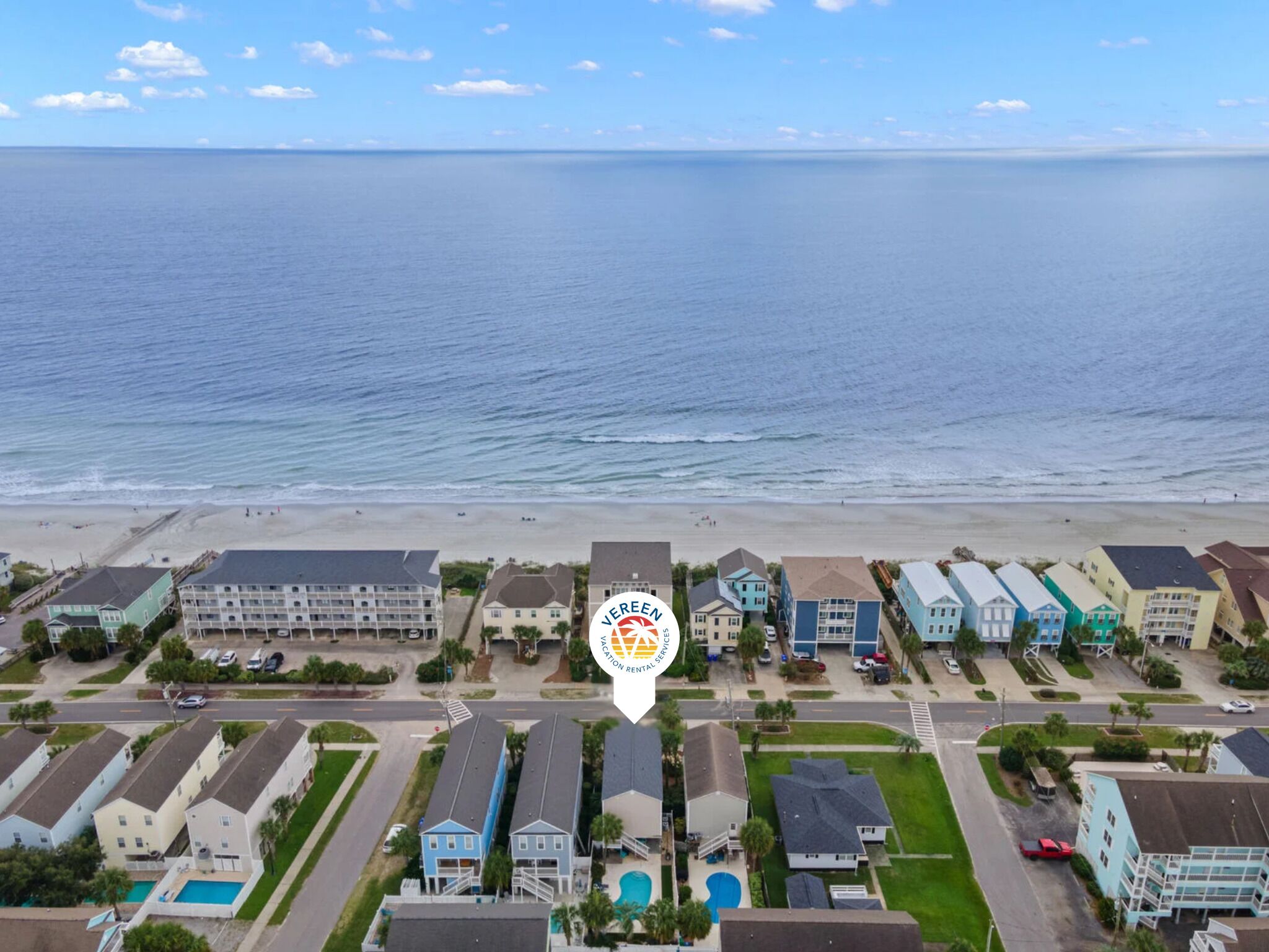 A coastal residential area with beachfront properties, a swimming pool, and a clear view of the ocean.