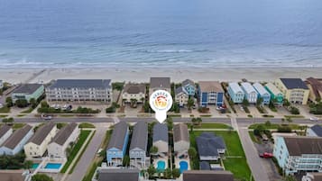 A coastal residential area with beachfront properties, a swimming pool, and a clear view of the ocean.