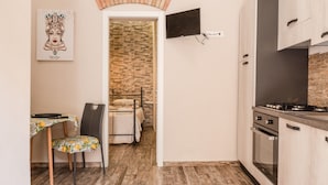 Eine kleine Küche mit Herd, Backofen und einem an der Wand befestigten Fernseher.