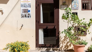 Ein Gebäude mit einer braunen Tür, einem Blumentopf und einem Poster an der Wand.