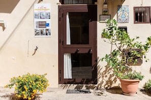 A building with a brown door, a potted plant, and a poster on the wall.