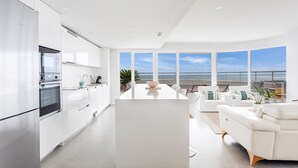 Una cocina moderna con una isla grande, armarios blancos y vistas al océano.
