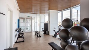 Un gimnasio con equipo de ejercicio, una banca y una puerta que da a otra habitación.