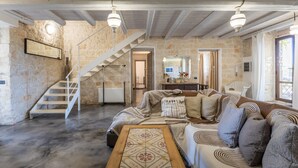 Ein geräumiger Wohnbereich mit Steinwand, Treppe, einer Sofagarnitur und einem Couchtisch.