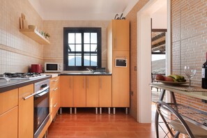 Una cocina con armarios de madera, un microondas, una estufa y una ventana con vistas.