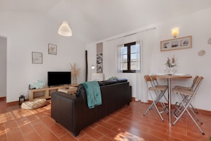 A living room with a sofa, TV, and dining table with chairs.