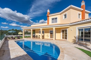 Uma casa com piscina, varanda coberta e uma grande janela.