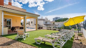 Una terrazza con lettini, un edificio giallo e una zona piscina.