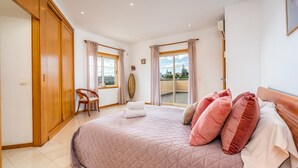 Una camera da letto con un letto grande, una sedia, una finestra con tende e vista sull'esterno.
