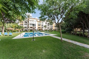 A pool area with lounge chairs, a building with balconies, and a well-maintained lawn. - Apartment 'Beautiful Frontline' with Shared Pool, Wi-Fi, and Air Conditioning (Unknown)