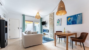 A modern living room with a sofa, dining table, chairs, and artwork on the walls. - Apartment 'Mi Patio, Port Of Cabopino' with Shared Pool, Wi-Fi and Air Conditioning (Unknown)