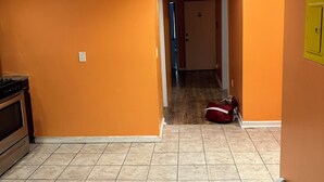 Un pasillo con paredes naranja, piso de baldosas y una puerta visible al final.
