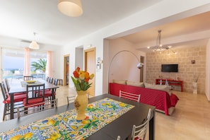 A dining area with a table set for four, a vase with flowers, and a view of the outdoors.