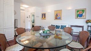 A dining area with a glass table, wicker chairs, and a white sofa. - Apartment 'Appartamento Gabbiano' with Shared Terrace, Wi-Fi and Air Conditioning (Rapallo)