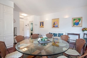 A dining area with a glass table, wicker chairs, and a white sofa.