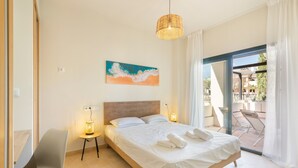 Un dormitorio con cama, lámparas de noche, un cuadro y vistas a través de un ventanal.