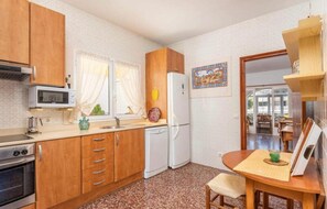 Une cuisine compacte dotée de meubles en bois, d’un four à micro-ondes, d’un réfrigérateur et d’un coin repas avec une table et des chaises.