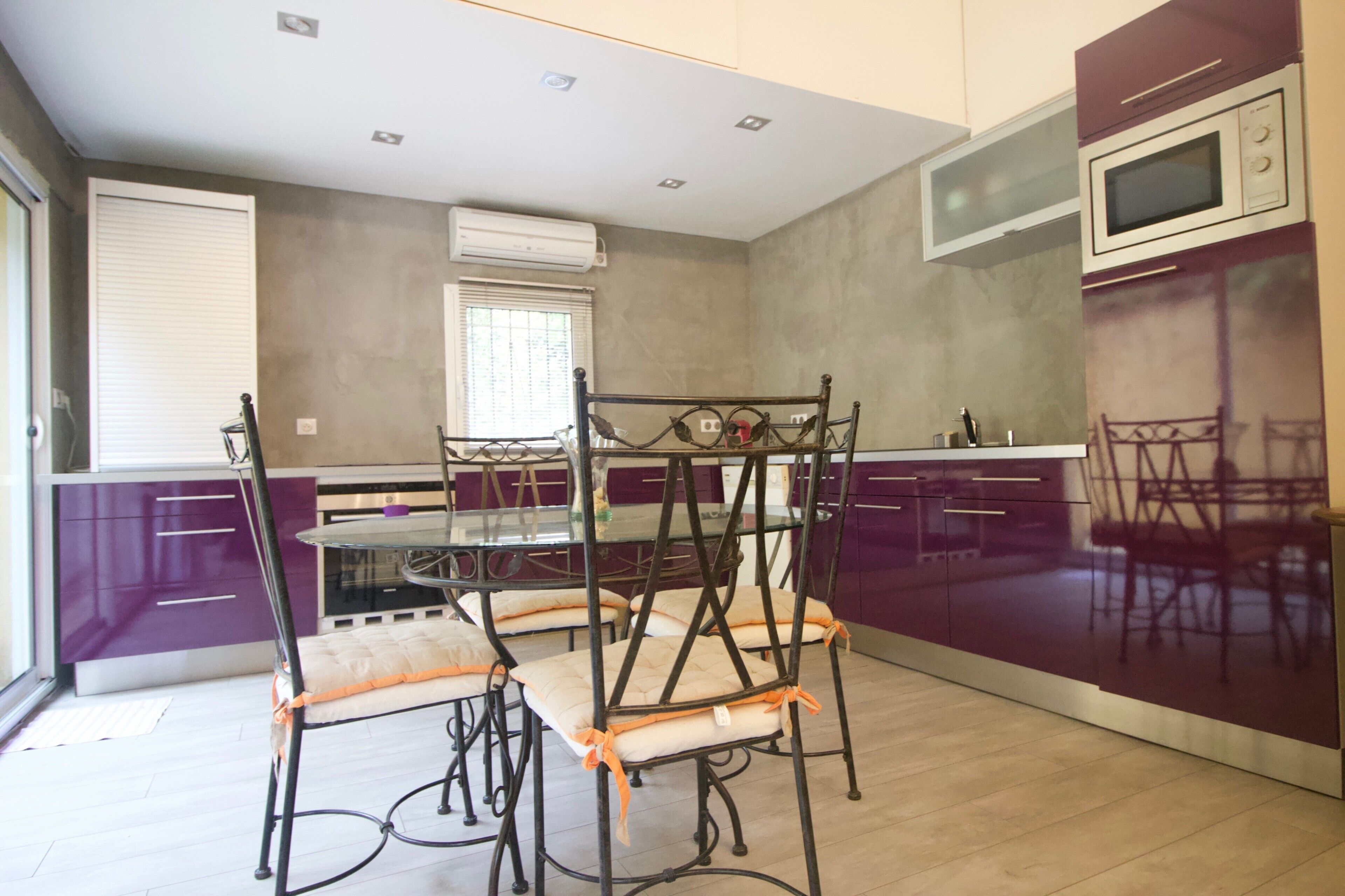 A modern kitchen with a dining table, chairs, and built-in appliances.