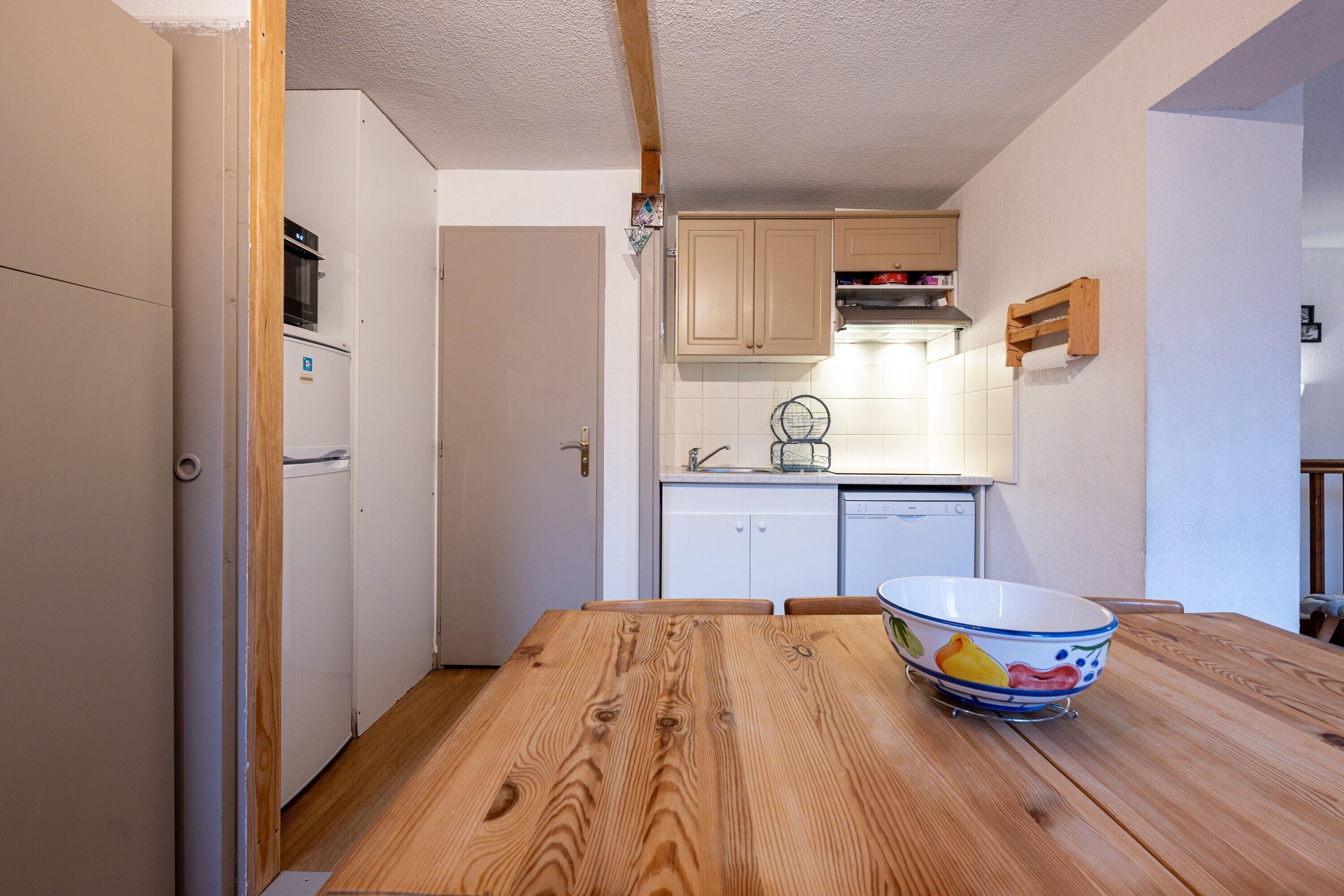 Eine kleine Küche mit Holztisch, Schüssel und Grundausstattung.