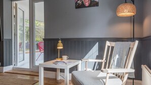 A room with a white table, a chair with a cushion, a lamp, and a painting on the wall. - The Red House, Leiston - A Smart Base for Coast and Work (Suffolk)