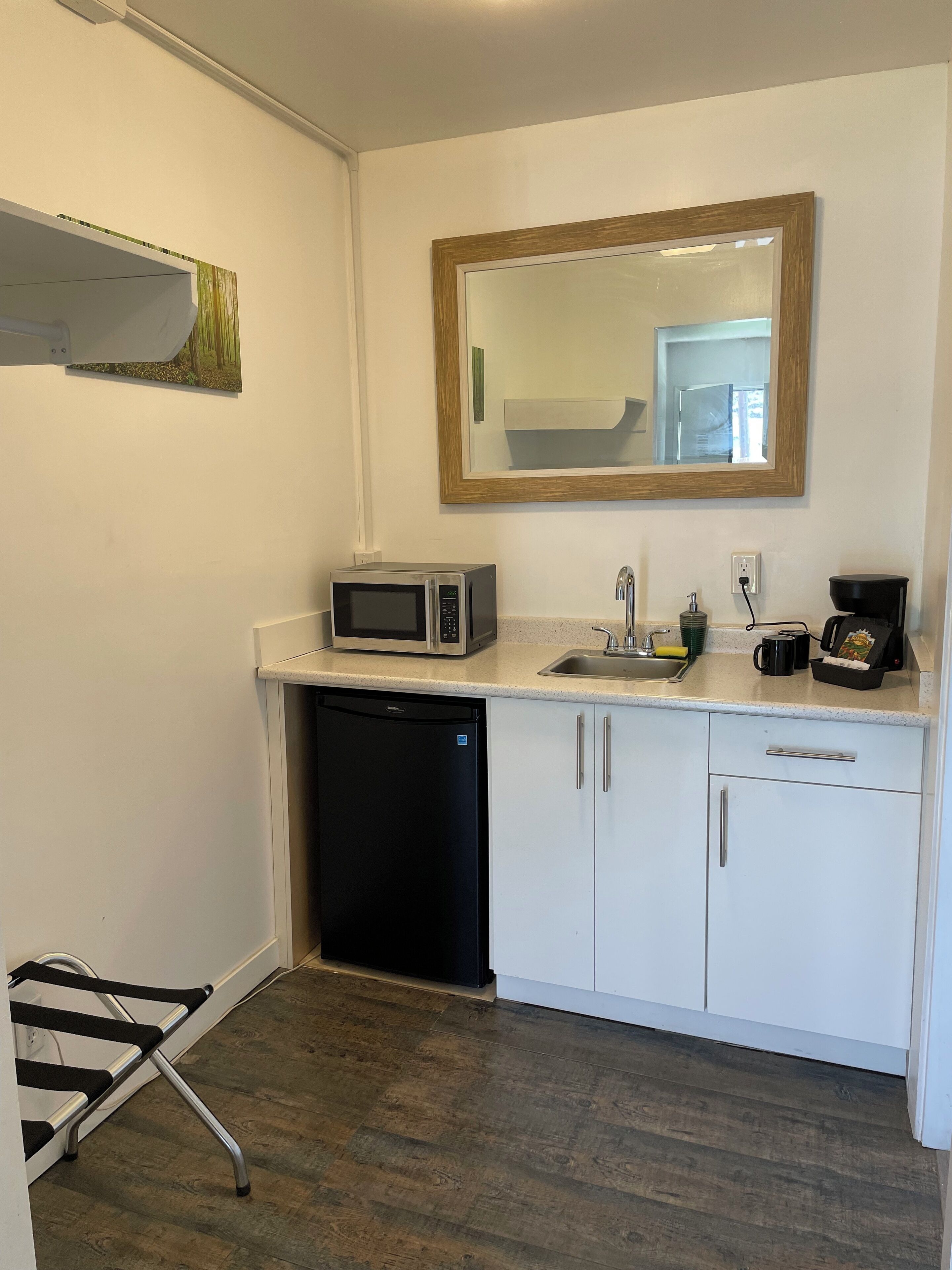 A compact kitchen with a microwave, sink, coffee maker, and dishwasher.