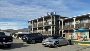 A motel with a two-story structure, a parking lot with several cars, and a clear sky. - Ashcroft Motel (Ashcroft)