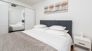 A bedroom with a bed, a nightstand, a bedside table, a mirror, and a painting on the wall. - Awesome home in Kosute (Kosute)