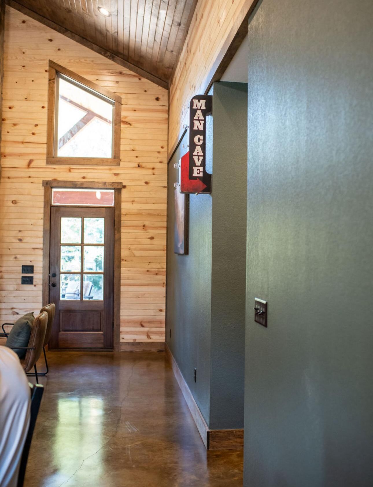 Een houten galerij met een deur naar een kamer, een raam en een bewegwijzer.
