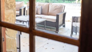 An outdoor patio with wicker furniture and a stone wall. - Cozy 4 bedroom Lodge close to I-30 and local wedding venues (Simms)