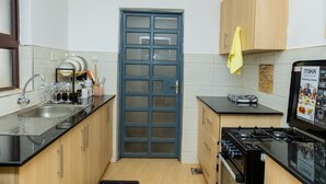 A compact kitchen with a black countertop, a stove, a sink, and wooden cabinets.