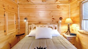 Een houten slaapkamer met een bed, een bedlampje en een digitaal klokje.