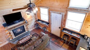 Een gezellig interieur van een chalet met een open haard, een televisie, een bar en een eethoek.