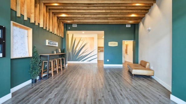 A reception area with a wooden ceiling, a reception desk, a sofa, and a wall-mounted sign. - Urban Elegance | 1BR LoHi Loft | City Views | Dog-Friendly (Denver)
