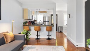 A modern kitchen with a central island, bar stools, and a dining area.