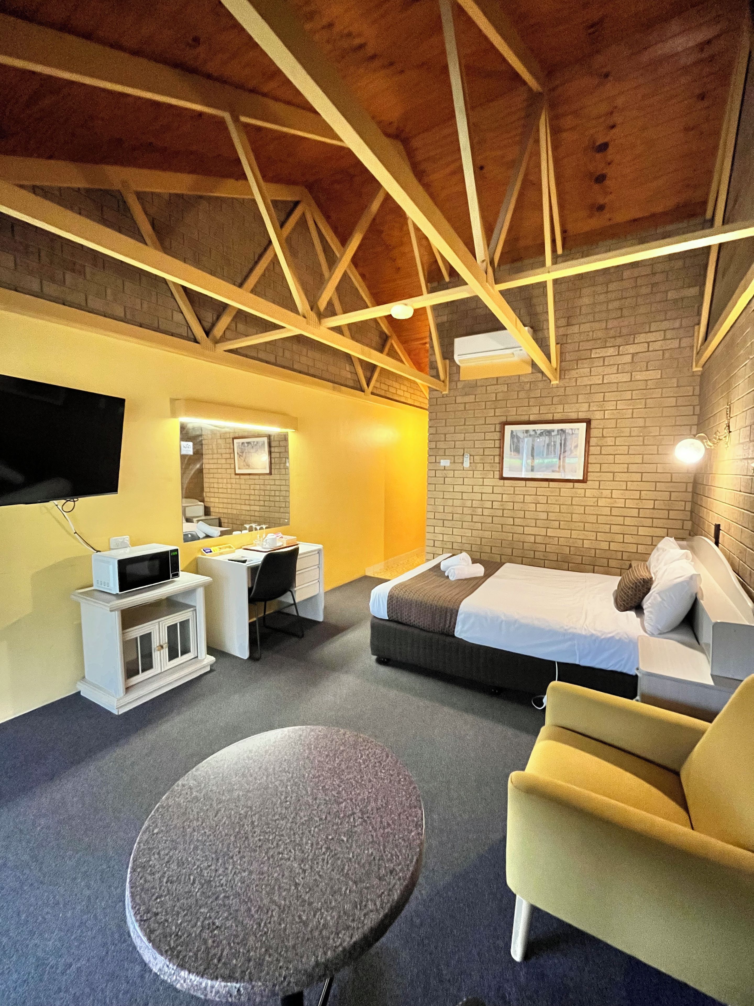 Habitación de hotel con cama, escritorio, silla, televisor y microondas.