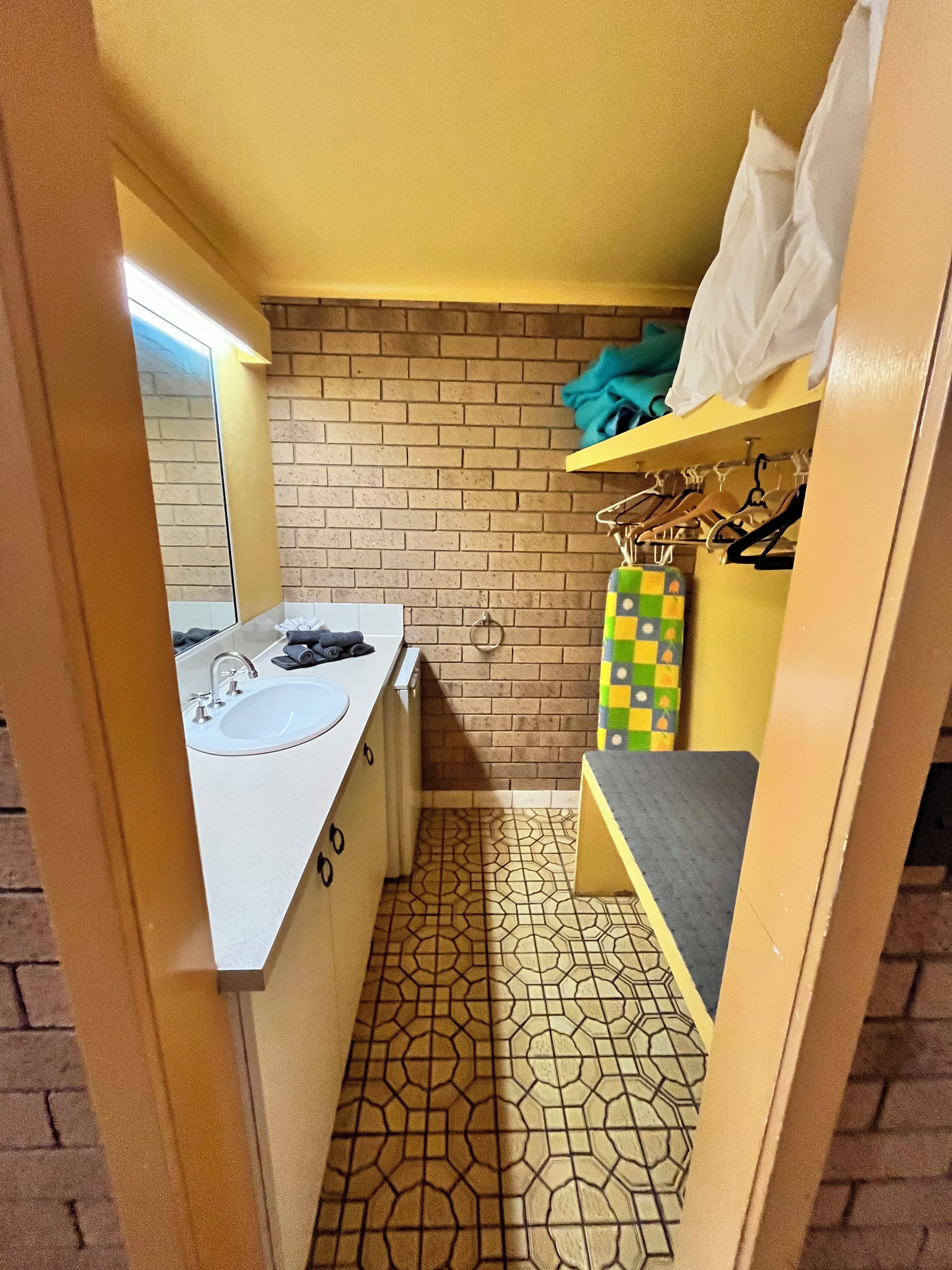 A small bathroom with a sink, mirror, and a shelf with towels.