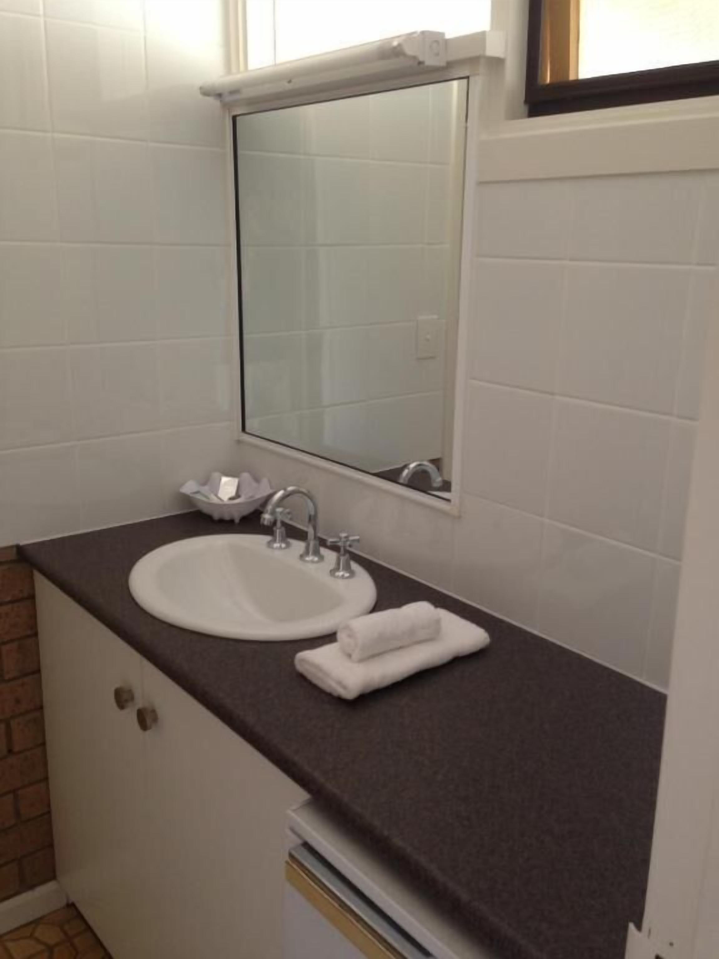 A bathroom with a white sink, a mirror, and a towel on the counter.