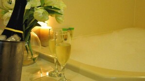 Una botella de champán, dos copas y una vela sobre un tocador de baño.