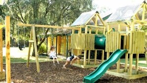 Un parque infantil con columpios, un tobogán y una estructura para escalar.