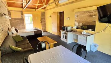 Una habitación acogedora con una cama, un sofá, una mesa de comedor y una zona de cocina con microondas.