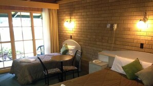 Habitación de hotel con dos camas, una mesita pequeña y una silla.