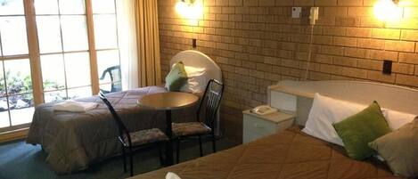 Habitación de hotel con dos camas, una mesita pequeña y una silla.
