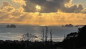 A coastal landscape with a sunset, calm sea, and distant islands. - Back to Basics at Iconic Wharekaho Bay (Simpsons Beach) Whitianga (Wharekaho)