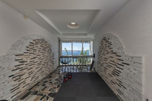 A corridor with a patterned brick wall, a pair of shoes, and a chair.