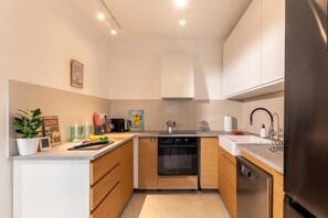 A modern kitchen with white cabinets, a built-in oven, a dishwasher, and a stainless steel refrigerator.