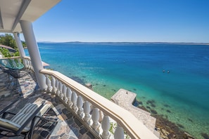 A balcony with a stone floor, a white balustrade, and a clear view of the sea. - Holiday Home Seafront Escape, Tribanj, Croatia (Tribanj)